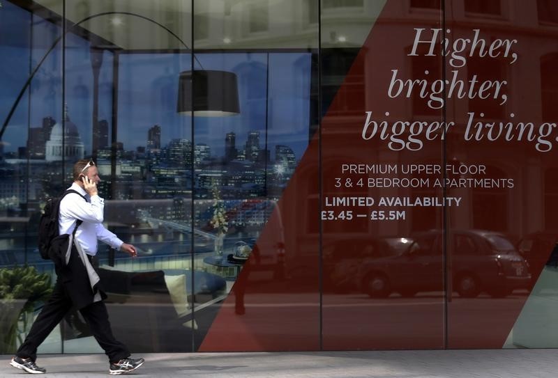 © Reuters. A man walks past the signage of a new property development advertising apartments for 5.5 million pounds sterling in central London
