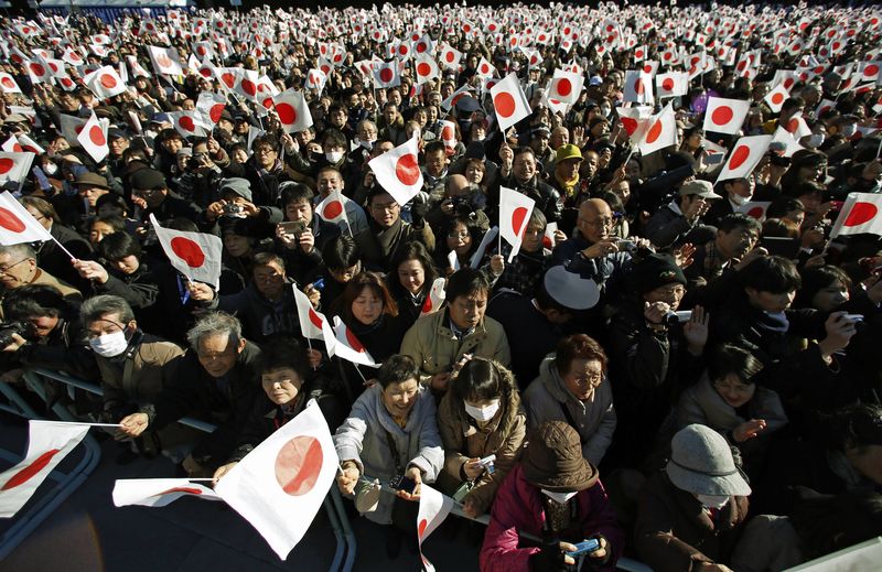 © Reuters. Japoneses acenam com bandeiras do país no aniversário de 81 anos do imperador Akihito, em Tóquio