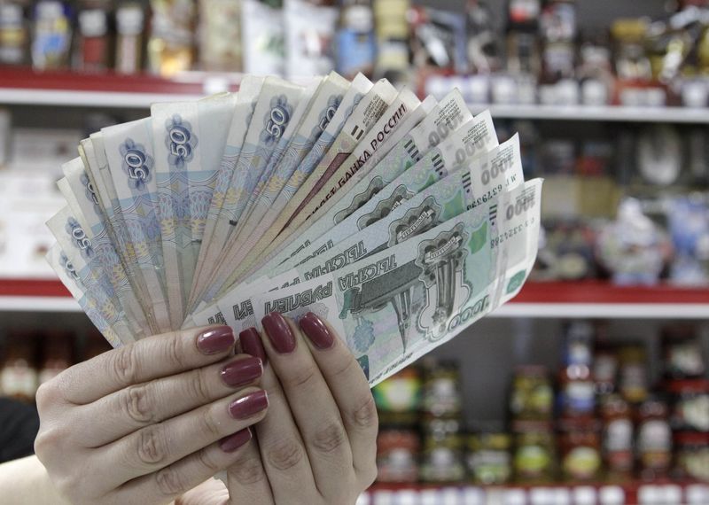 © Reuters. A cashier displays Russian rouble banknotes taken from a cash register at a local grocery store in Stavropol