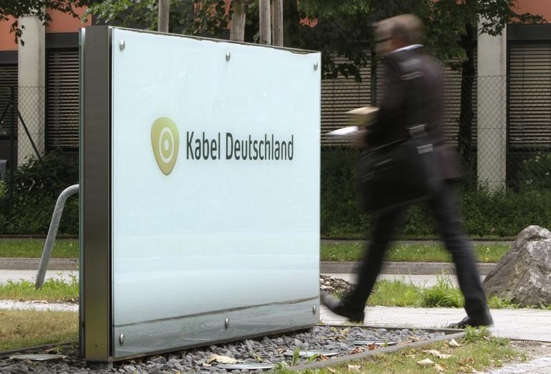 © Reuters. A man passes the company logo of German cable television group Kabel Deutschland in Unterfoehring