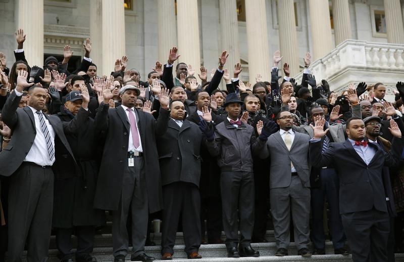 © Reuters. African-American Congressional staffers stage walk out with Hands Up Don't Shoot pose on the steps of the House of Representatives in Washington to protest the deaths of Michael Brown and Eric Garner