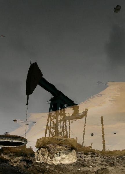 © Reuters. Станок-качалка отражается в луже нефти в Баку