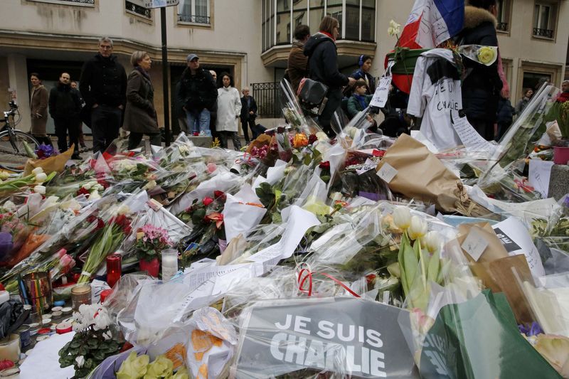 © Reuters. Pessoas fazem homenagem em frente ao jornal semanal de sátiras Charlie Hebdo, em Paris