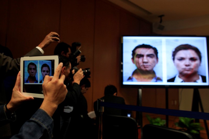 © Reuters. Media take pictures of mugshots of Jose Luis Abarca, former mayor of Iguala, and his wife Maria de los Angeles during a news conference in Mexico City