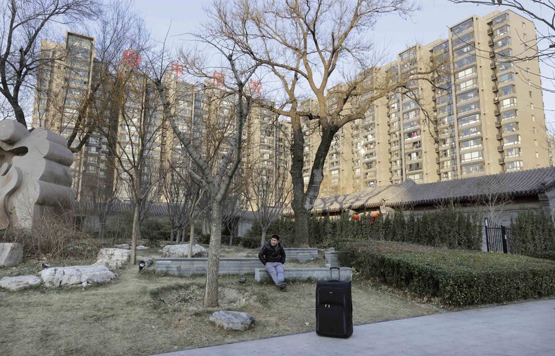 © Reuters. A man sits near apartment blocks in central Beijing