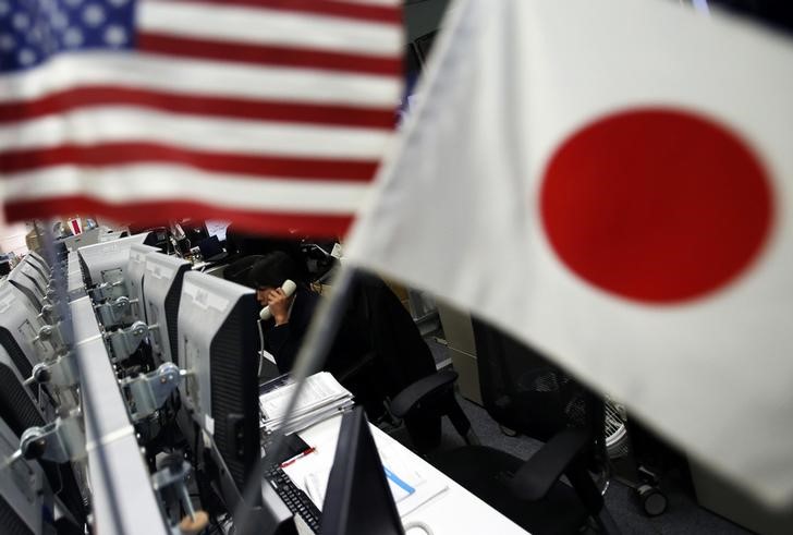 © Reuters. An employee of a foreign exchange trading company working is seen between the national flags of Japan and the U.S. in Tokyo