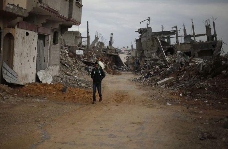 © Reuters. Palestinian walks near the remains of houses, that witnesses said were destroyed or damaged by Israeli shelling during the July-August war between Israel and Hamas-led Gaza militants, in the east of Gaza City