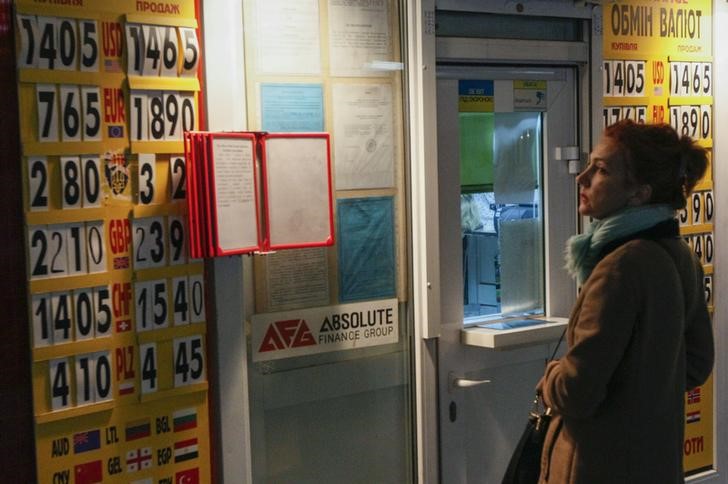 © Reuters. A woman looks at a board showing currency exchange rates in Kiev