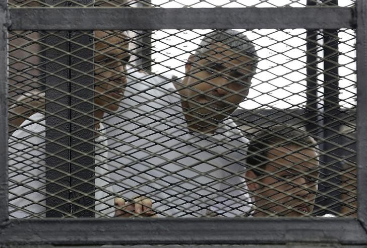 © Reuters. Peter Greste, Mohamed Fahmy and Baher Mohamed listen to the ruling at a court in Cairo