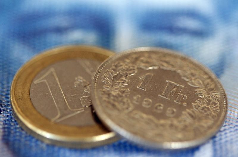 © Reuters. Монеты 1 евро и 1 швейцарский франк лежат на банкноте 100 франков