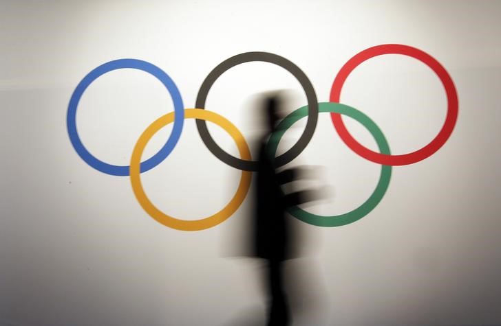 © Reuters. A man walks past the Olympic rings before the opening of the 127th International Olympic Committee session in Monaco