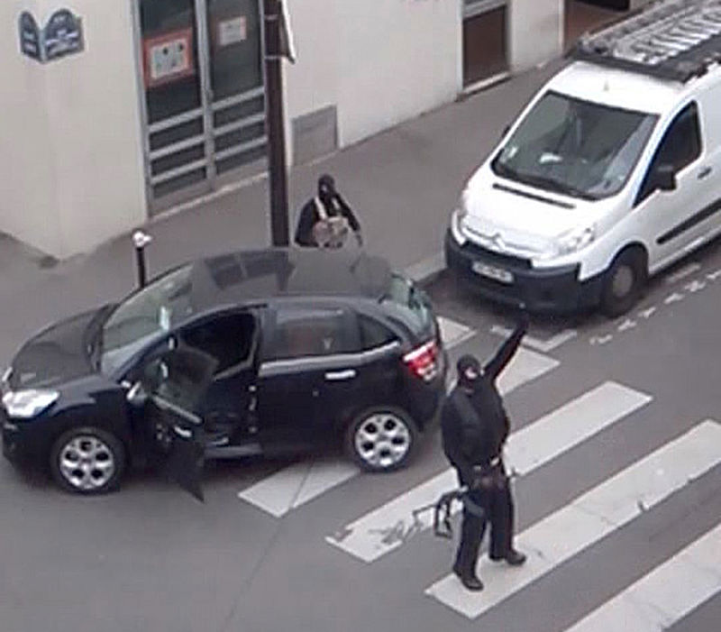 © Reuters. Gunmen gesture as they return to their car after the attack outside the offices of French satirical weekly newspaper Charlie Hebdo