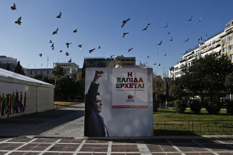 © Reuters. A flock of pigeons flies over a banner with an image of Tsipras at the party's pre-election kiosk in Athens