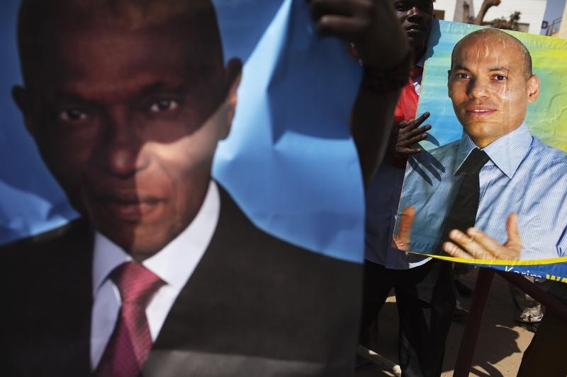 © Reuters. Supporters of PDS hold posters of former Senegalese president Wade and son Karim at protest in Dakar