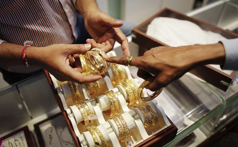 © Reuters. An employee shows gold bangles to a customer at jewellery showroom on the occasion of Dhanteras, a Hindu festival associated with Lakshmi, the goddess of wealth, at a market in Mumbai