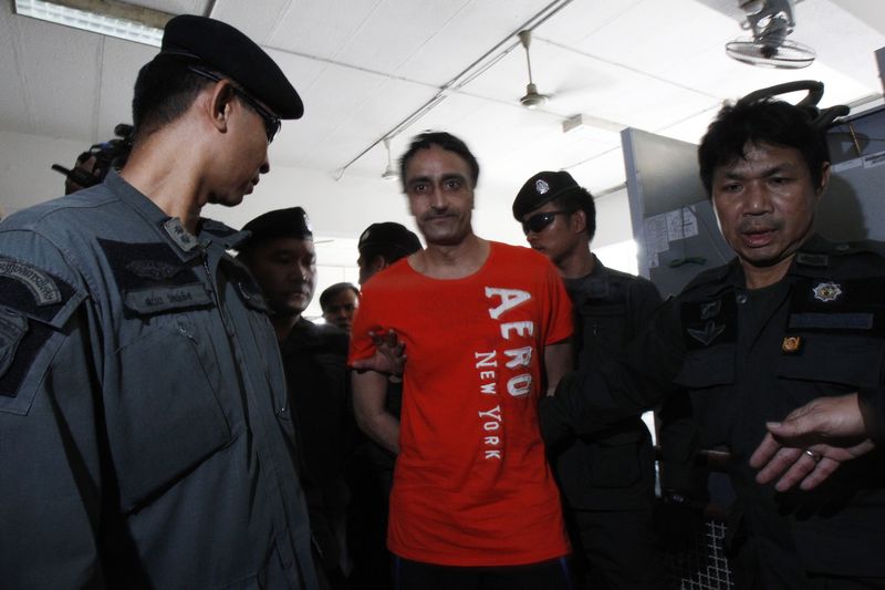 © Reuters. Police officers escort Gurmeet Singh, also known as Jagtar Singh Tara, from India, as they arrive at the criminal court in Bangkok