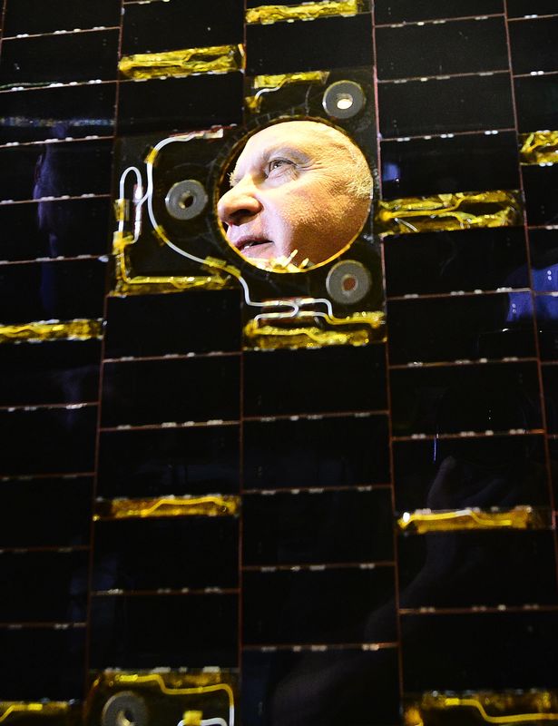 © Reuters. Beagle 2 Mission Manager, Mark Sims, looks through a solar panel the same as used on Beagle 2, following a news conference in London