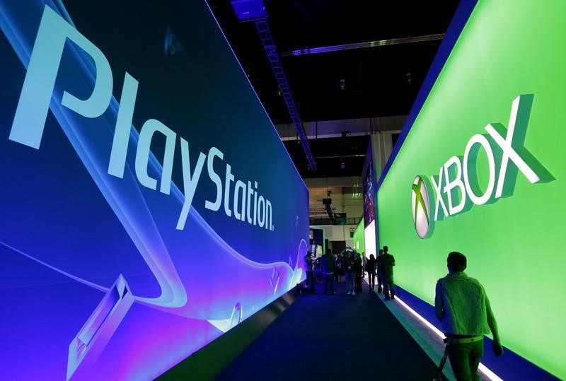 © Reuters. People walk past the Playstation and Xbox booths at the 2014 Electronic Entertainment Expo, known as E3, in Los Angeles