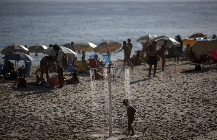 © Reuters. Menino se refresca em chuveiro  na praia do Arpoador, no Rio de Janeiro