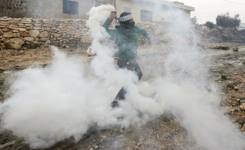 © Reuters. Manifestante palestino joga bomba de gás lançada por soldado israelense