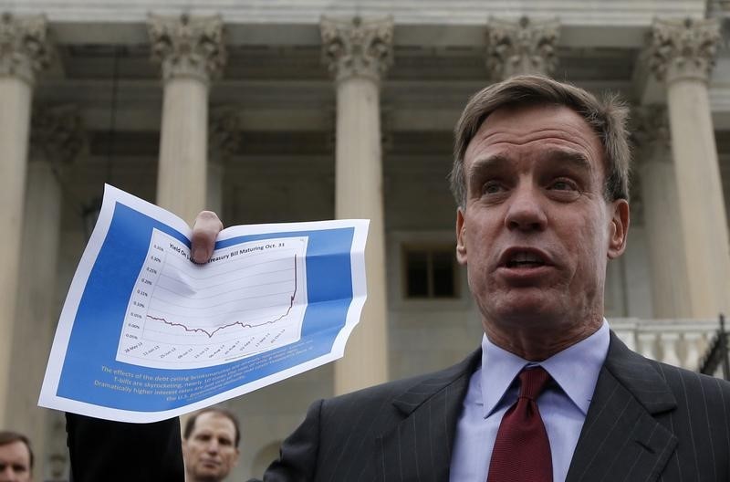 © Reuters. U.S. Senator Mark Warner holds up a graph of the one month treasury bond yield increase already being affected by the U.S. debt ceiling debate brinkmanship, on the steps of the U.S. Capitol in Washington