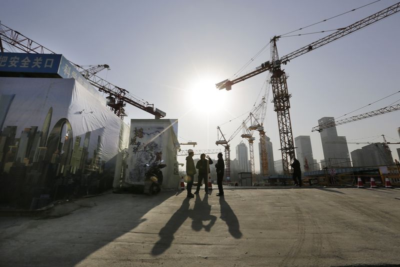 © Reuters. Workers chat outside a construction site in Beijing's central business district