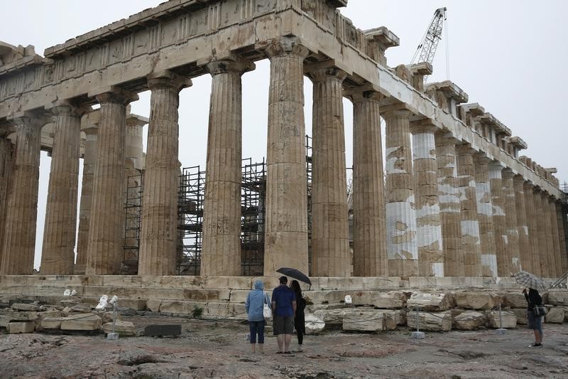 © Reuters. Tourists look at the temple of the Parthenon on the Acropolis hill on the eve of the World Tourism Day in Athens