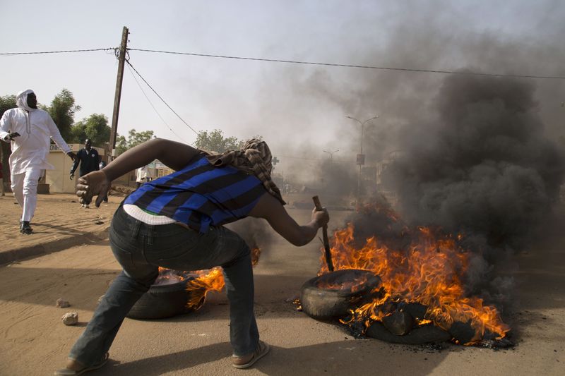© Reuters. A man burns a tire during a protest against Niger President Issoufou's attendance last week at a Paris rally in support of French satirical weekly Charlie Hebdo, in Niamey
