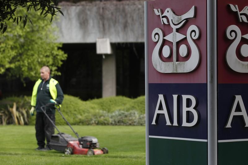 © Reuters. A gardener mows the grass outside the headquarters of AIB on the day the bank announced it's results, in Dublin