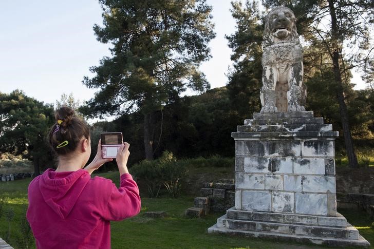 © Reuters. Menina tira foto de leão de mármore perto de local de escavação arqueológica na cidade de Amphipolis, no norte da Grécia