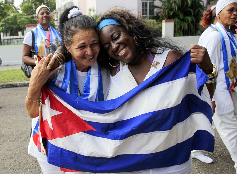 © Reuters. Recently released dissidents Haydee Gallardo and Sonia Garro hold the Cuban national flag during a march in Havana