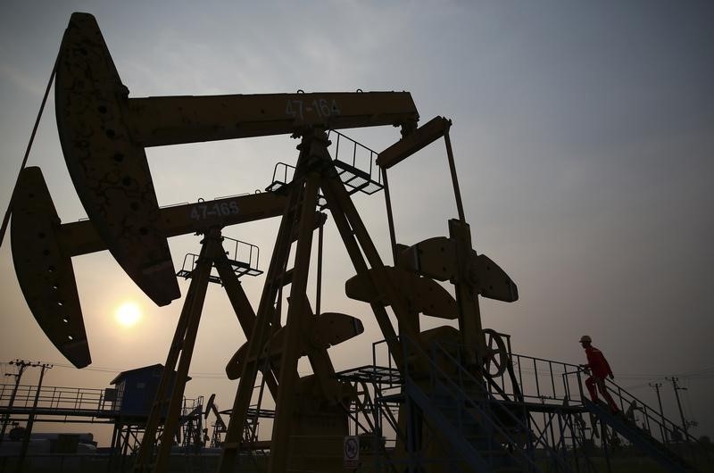 © Reuters. A worker examines a pumpjack at a PetroChina oil field in Panjin