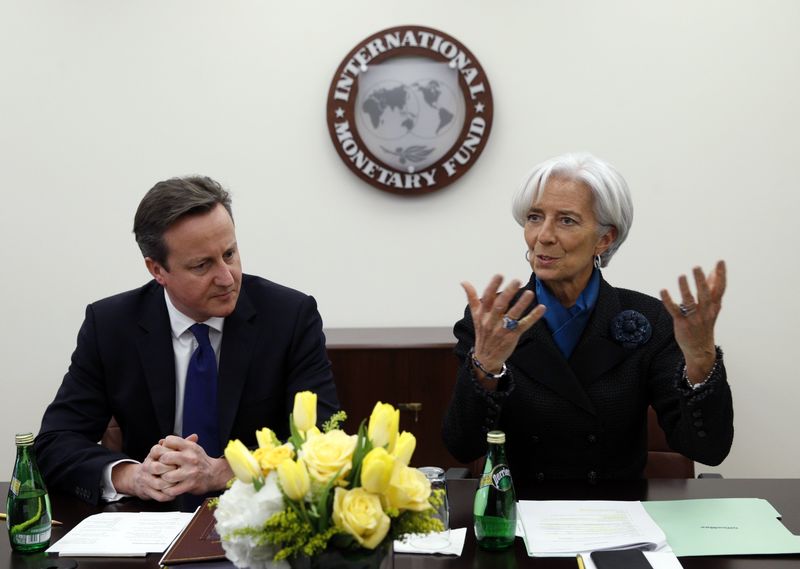 © Reuters. British Prime Minister Cameron listens as IMF Managing Director Lagarde speaks at a Global Economy roundtable discussion at the International Monetary Fund in Washington