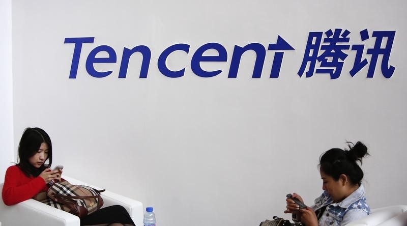 © Reuters. Visitors use phones underneath of logo of Tencent at Global Mobile Internet Conference in Beijing