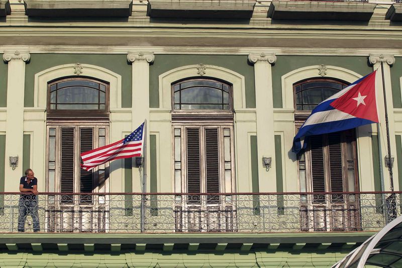 © Reuters. Man stands near national flags of U.S. and Cuba on balcony of a hotel being used by first U.S. congressional delegation to Cuba since change of policy announced by U.S. President Obama, in Havana