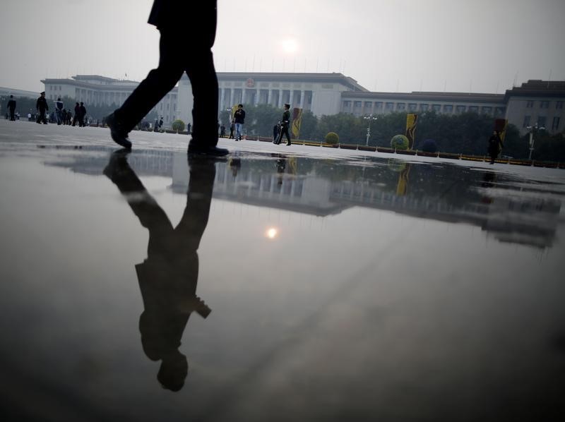 © Reuters. A paramilitary policeman and pedestrians are reflected on water in front of the Great Hall of the People in Beijing