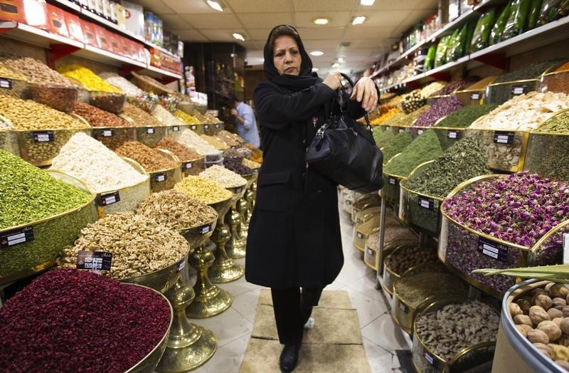 © Reuters. A woman walks in a shop at a bazar in Tehran