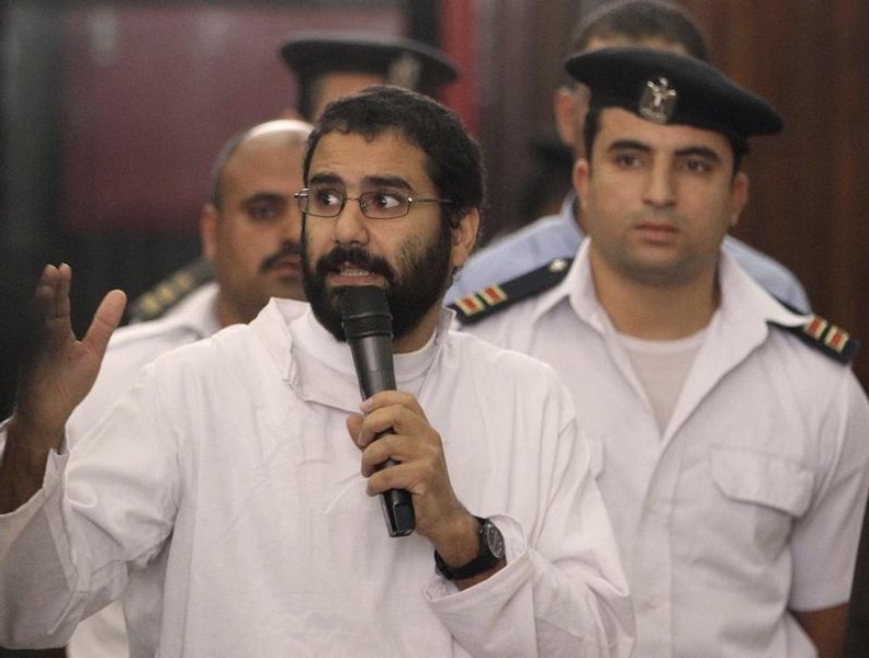 © Reuters. Activist Alaa Abdel Fattah speaks in front of a judge at a court during his trial in Cairo