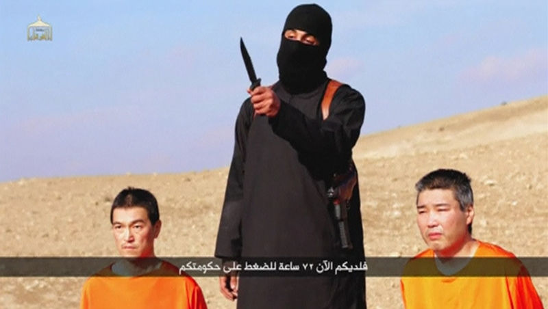 © Reuters. A masked person holding a knife speaks as he stands in between two kneeling men in this still image taken from an online video released by the militant Islamic State group