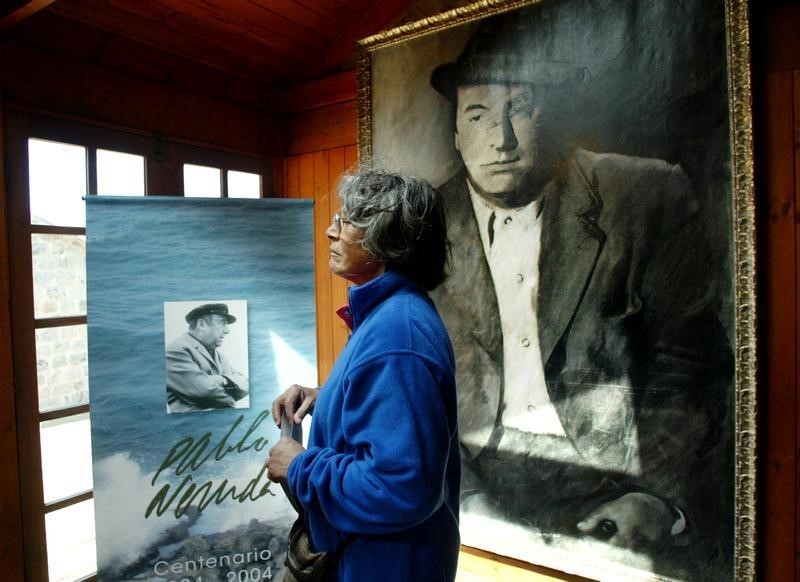 © Reuters. A woman looks at a painting of Chilean poet and Nobel laureate Pablo Neruda during a ceremony the 30..