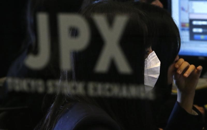 © Reuters. A visitor wearing a mask is seen behind a logo of Japan Stock Exchange (JPX) at the Tokyo Stock Exchange in Tokyo