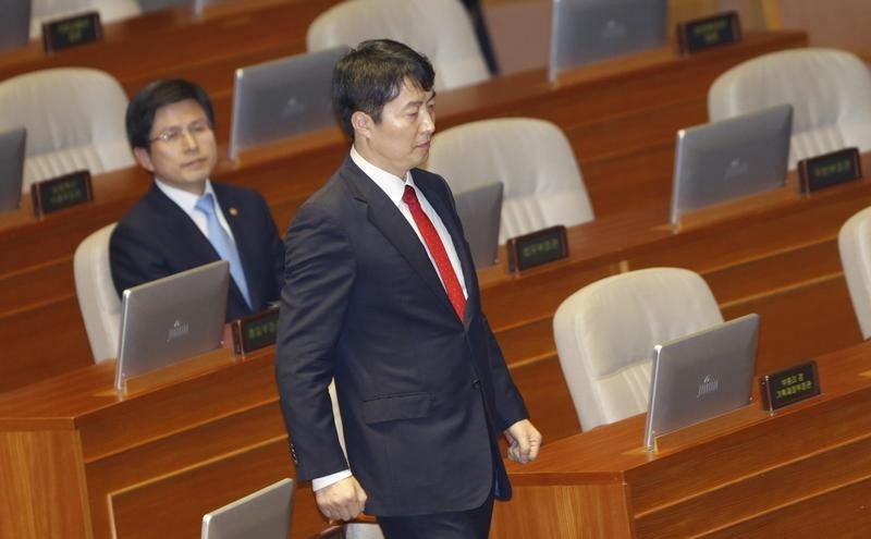 © Reuters. Lee Seok-Ki, lawmaker of opposition United Progressive Party, walks to deliver his speech as Justice Minister Hwang Kyo-ahn looks at him during a plenary session at parliament in Seoul
