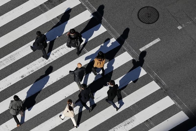 © Reuters. Pedestrians cast shadows on the crosswalk near the headquarters of the Bank of Japan in Tokyo