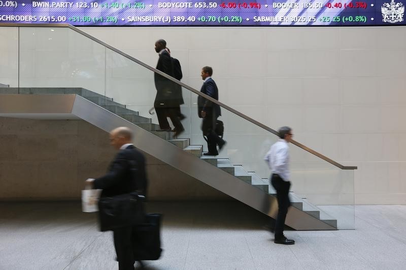© Reuters. People walk past an electronic information board at the London Stock Exchange in the City of London