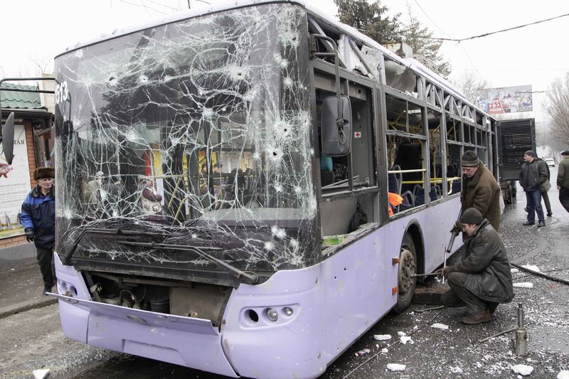 © Reuters. Pessoas ao redor de ônibus destruído por ataque em Donetsk