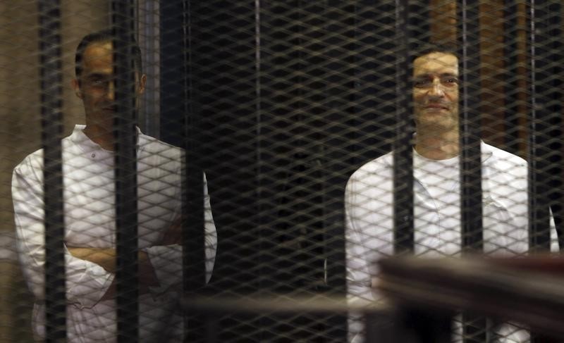 © Reuters. Gamal and Alaa Mubarak, sons of former President Hosni Mubarak, smile during their trial at the police academy, on the outskirts of Cairo