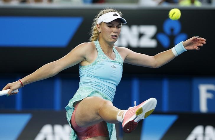 © Reuters. Caroline Wozniacki of Denmark kicks a tennis ball in frustration during her women's singles second round match against Victoria Azarenka of Belarus at the Australian Open 2015 tennis tournament in Melbourne 