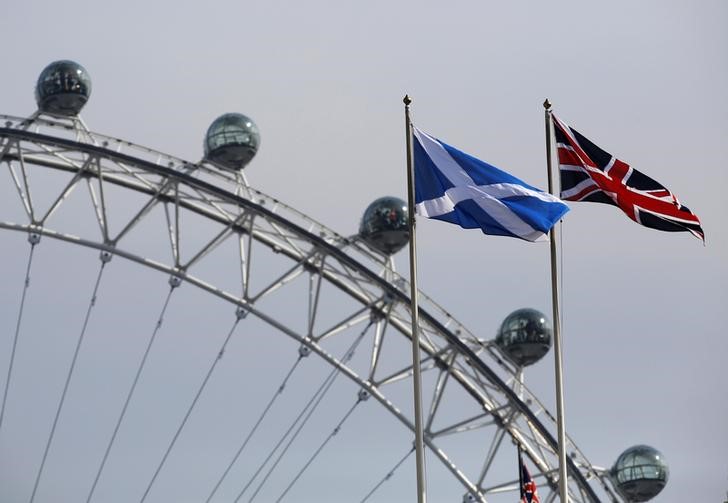 © Reuters. A Scottish Saltire flag and British Union flag fly together with the London Eye behind in London