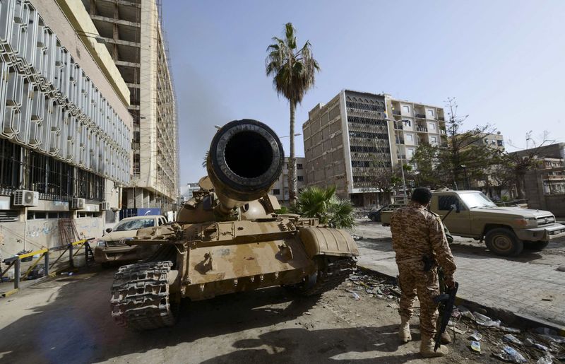 © Reuters. A member of the Libyan pro-government forces, backed by locals, stands near a tank outside the Central Bank, near Benghazi port