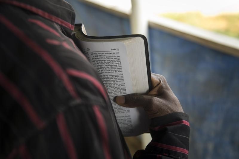© Reuters. A member of the clergy reads from the Bible to Ebola Patients in the recovery wing of the Hastings Ebola treatment centre in a neighbourhood in Freetown